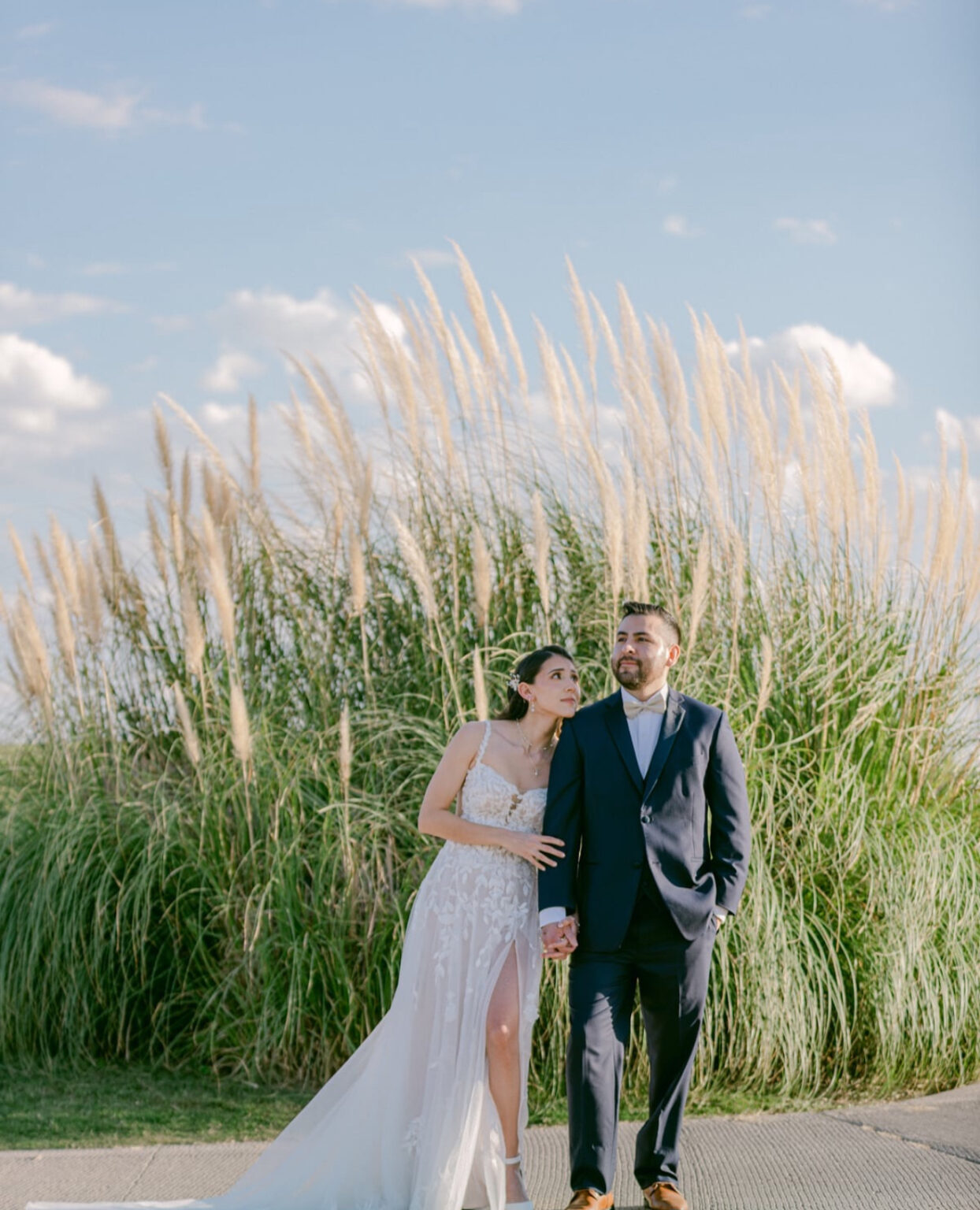 Bride and groom pose for a romantic wedding portrait in front of tall pampas grass at Painted Dunes Desert Golf Course in El Paso, showcasing the natural desert landscape and elegant golf course wedding setting.